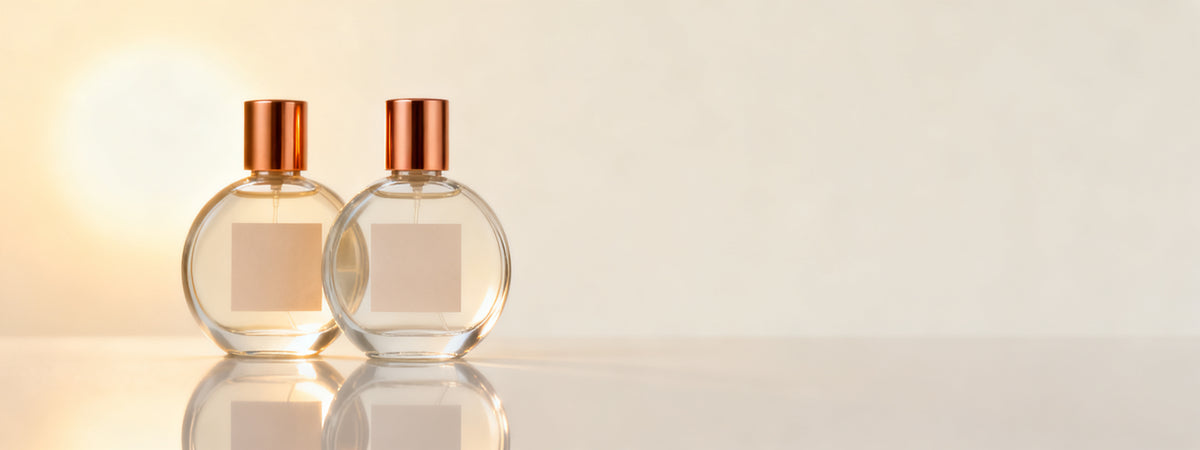 Dois frascos arredondados de perfume adocicado Lescent em luz quente e dourada